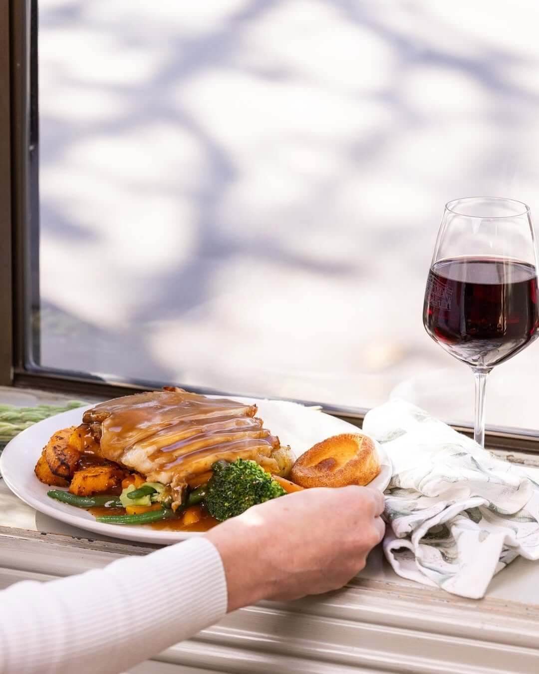 A plate topped with a Christmas lunch and a glass of red wine